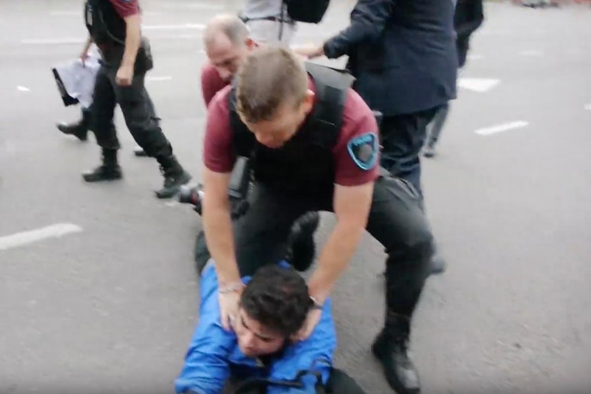 A male Falun Gong practitioner is pinned down by Argentine police. (Screenshot via YouTube)