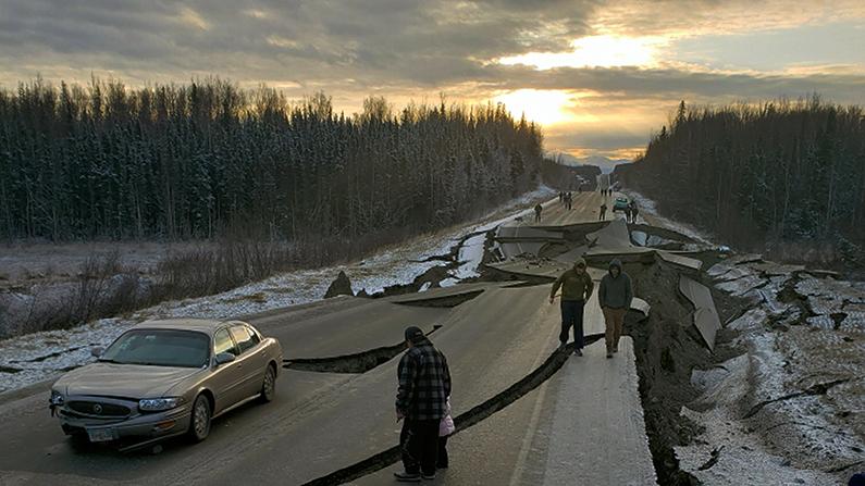People walk along Vine Road in Wasilla, Alaska, after the 7.0 earthquake, on Nov. 30, 2018, (Jonathan M. Lettow via AP)