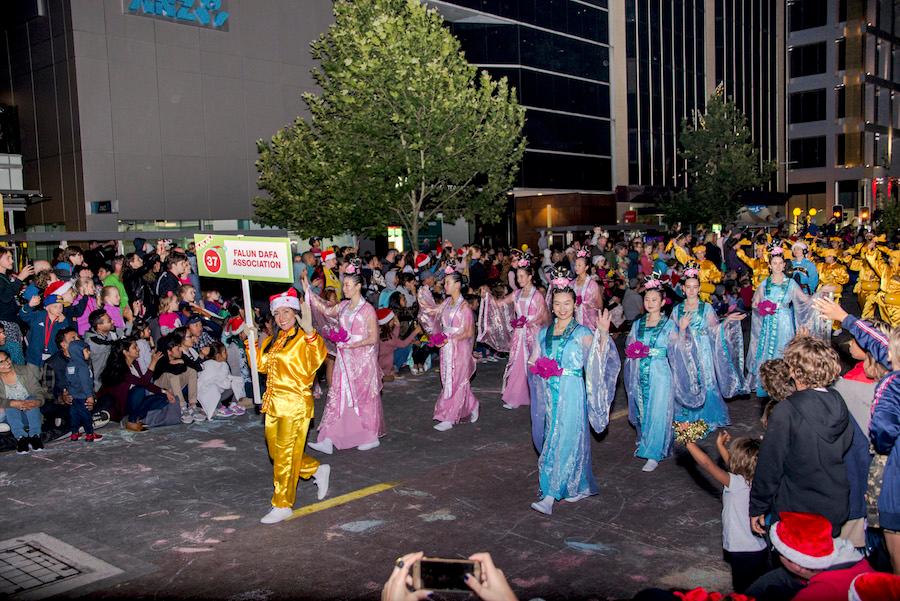 The Falun Gong community holds a sign as they walk through a parade in the annual Christmas Pageant in Perth, Australia, on Dec. 1, 2018. (Sam Lin/The Epoch Times)