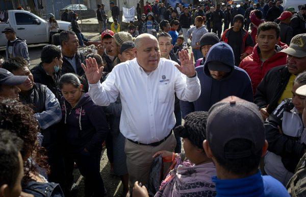 Luis Bustamante, an official from the Mexican state of Baja California, tries to answer questions from a group of Central American migrants, as they decide whether to relocate another shelter in Tijuana, Mexico, on Nov. 30, 2018. (AP Photo/Gregory Bull)
