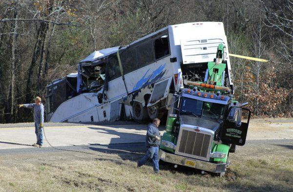 Employees from a wrecker service work to remove a charter bus from a roadside ditch Dec. 3, 2018, after it crashed alongside Interstate 30 near Benton, Ark. (Josh Briggs/Saline Courier via AP)