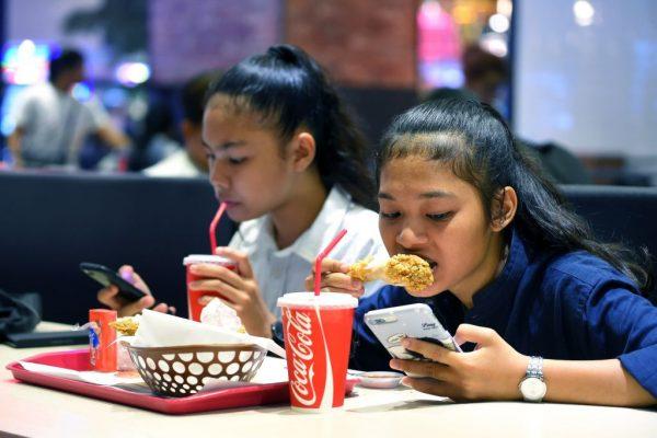 Cambodian teenagers use phones while eating at a restaurant in Phnom Penh on Oct. 28, 2018. (Tang Chhin Sothy/AFP/Getty Images)