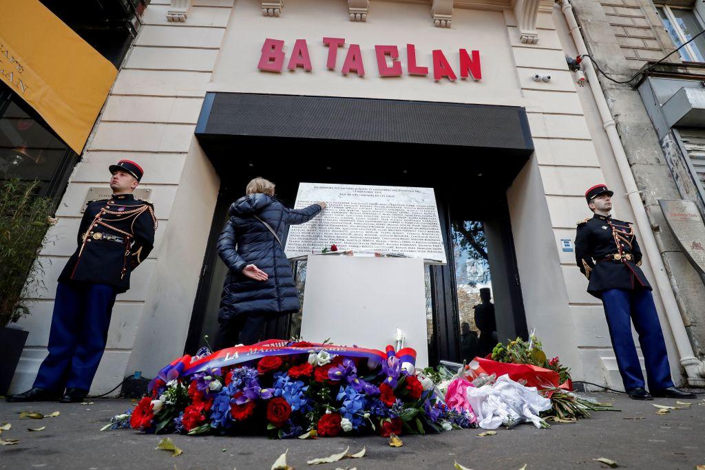 A woman touches the commemorative plaque at the entrance of the Bataclan in Paris on Nov. 13, 2018, during a ceremony held for the victims of the Paris attacks of November 2015, which targeted the Bataclan concert hall as well as a series of bars and killed 130 people. (Tessier/AFP/Getty Images)