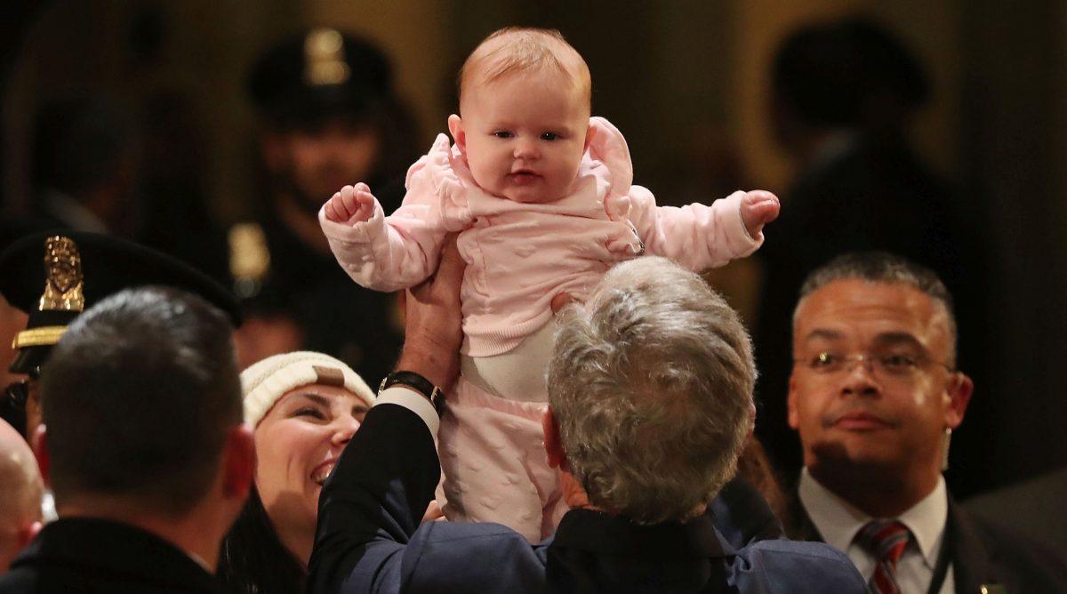 Former U.S. President George W. Bush holds up 5-month-old Sienna Collett while greeting mourners in front of the casket (Photo by Mark Wilson/Getty Images)
