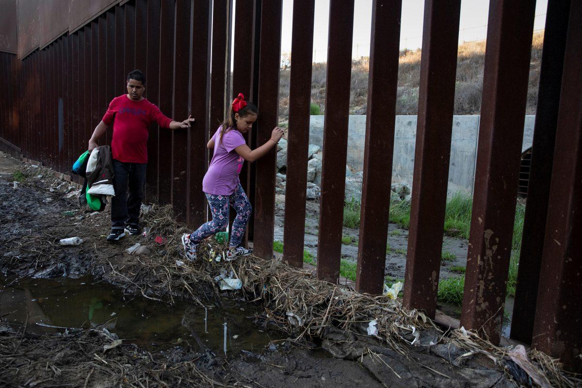 Tony Mauricio Arita, 33 and his daughter Andrea Nicole, 10, from Honduras, part of a caravan of thousands from Central America trying to reach the United States, move next to a border wall before crossing illegally from Mexico to the U.S, in Tijuana, Mexico, on Dec. 4, 2018. (Alkis Konstantinidis/Reuters)