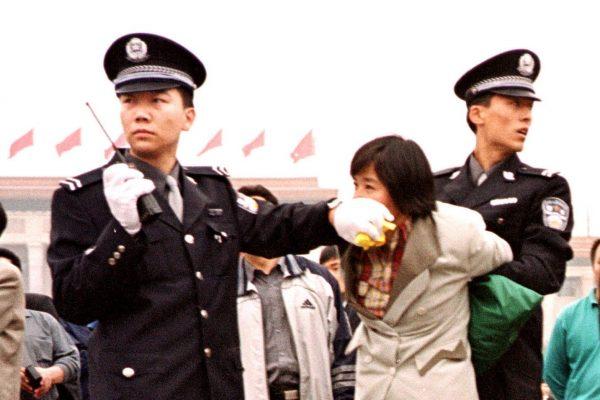 Two Chinese police officers arrest a female Falun Gong practitioner at Tiananmen Square in Beijing on Jan. 10, 2000. The persecution of Falun Gong has continued for nearly 20 years. (Chien-Min Chung/AP Photo)