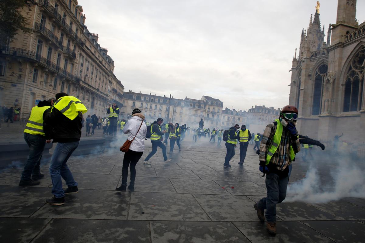 Protesters wearing yellow vests walk through tear gas during clashes with police at a demonstration of the "yellow vests" movement in Bordeaux, France, December 8, 2018. REUTERS/Regis Duvignau