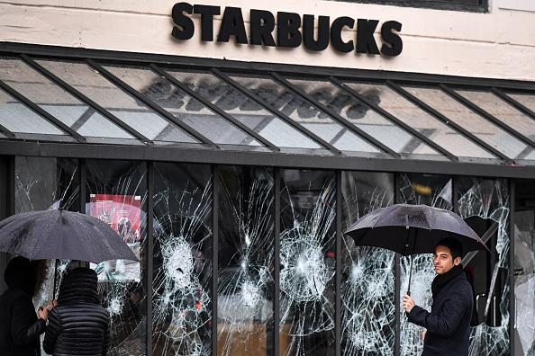 Members of the public view graffiti and broken a window of a Starbucks at Gare Saint – Lizare following a fourth week of protests against rising fuel prices on Dec. 9, 2018 in Paris, France. (Jeff J Mitchell/Getty Images)