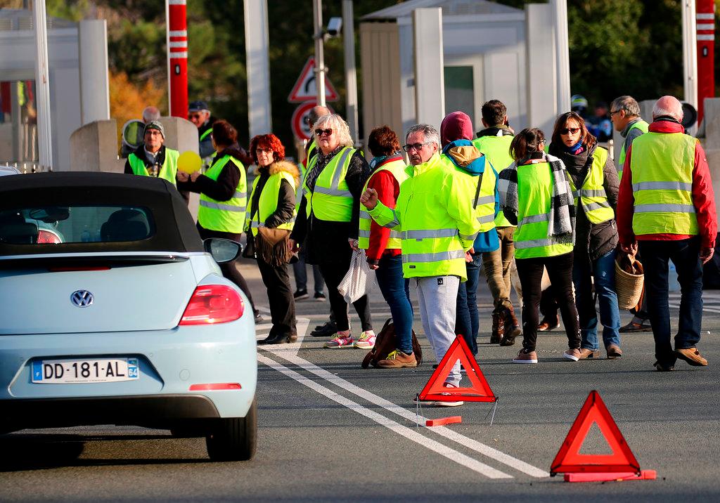 Demonstrators wearing yellow vests protest at the toll gates of a motorway, in Biarritz, southwestern France, on Dec. 10, 2018. (AP Photo/Bob Edme)