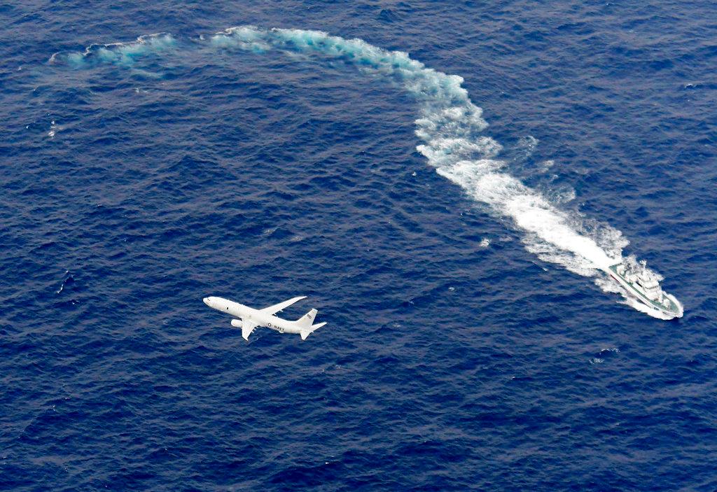 Japan's Coast Guard ship, top, and U.S. military plane are seen at sea off Kochi, southwestern Japan, during a search and rescue operation for missing crew members of an American Marines aircraft on Dec. 6, 2018. (Kyodo News via AP, File)