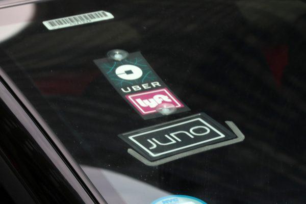 The Uber, Lyft, and Juno logos are on a car as it drives up Sixth Avenue in New York City, July 27, 2018. (Mike Segar/File Photo/Reuters)