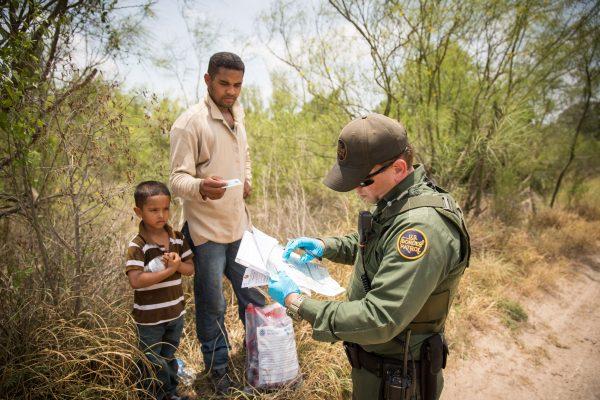 A Border Patrol agent takes down information of a man and his son who illegally crossed the Rio Grande from Mexico into the United States in Hidalgo County, Texas, on May 26, 2017. (Benjamin Chasteen/The Epoch Times)