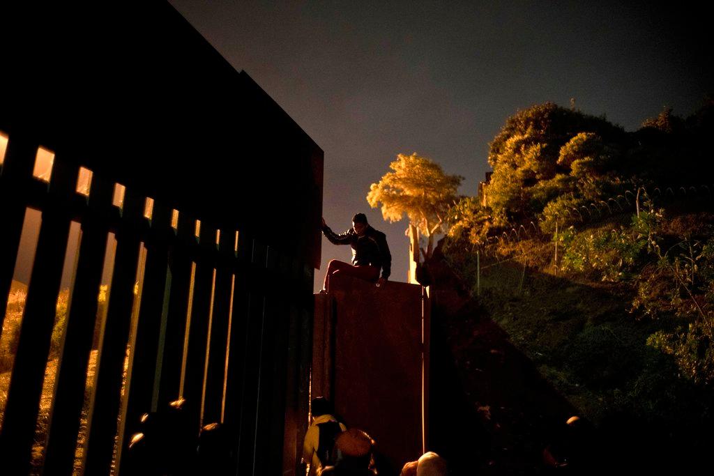 A Honduran migrant climbs the border wall separating Tijuana, Mexico and San Diego in Tijuana, Mexico, on Nov. 29, 2018. (AP Photo/Ramon Espinosa)