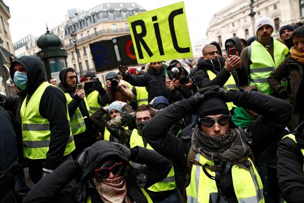 Protesters wearing yellow vests kneel on the street as they gather in front of the Opera House as part of the "yellow vests" movement in Paris, France, Dec. 15, 2018. (Reuters/Christian Hartmann)
