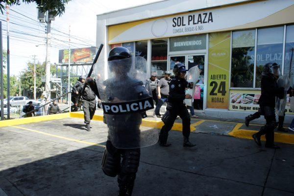 A police officer holds a baton and approaches journalists at the entrance to police headquarters in Managua, Nicaragua December 15, 2018. (Reuters/Oswaldo Rivas)