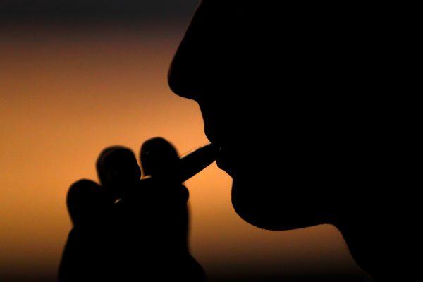 A young man smokes an electronic cigarette in this picture illustration taken on Sept. 14, 2018. (Mike Blake/Illustration/Reuters)