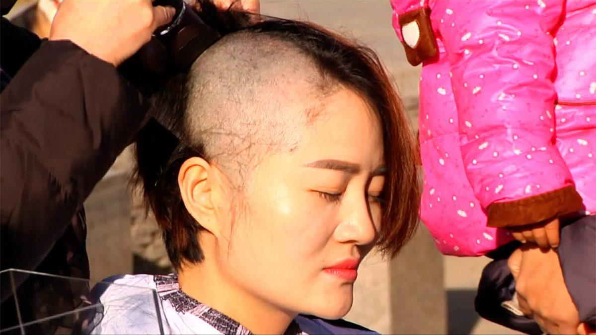 Li Wenzu, wife of detained human rights lawyer, Wang Quanzhang, gets her head shaved in Beijing in protest over the Chinese regime's lawlessness on Dec. 17, 2018. (Reuters)