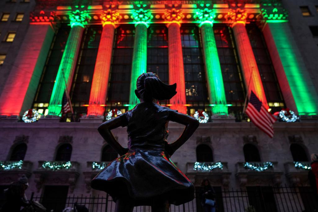 The 'Fearless Girl' statue stands across from the New York Stock Exchange (NYSE) as it is lit for the holidays with red and green light on Dec. 17, 2018. (Drew Angerer/Getty Images)