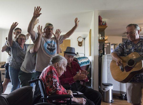 Don West, center, sings and claps along to the song "You are my Sunshine," at Golden Days II Adult Foster Care nursing home in Charlotte, Mich., on Aug. 21, 2018. as friends and family dance behind them. His wife Jackie had a stroke in June of 2017 and has been at the home since. (Matthew Dae Smith/Lansing State Journal via AP)