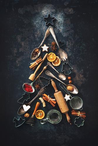 Christmas baking background with fir tree made from kitchen utensils, cookies, spices, cinnamon sticks, anise stars on rustic baking tray, top view - Image. (Shutterstock)