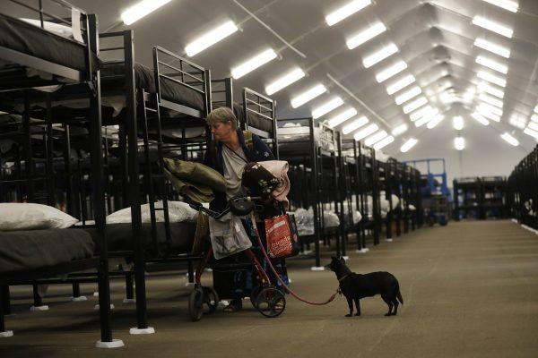 Verna Vasbinder prepares her new bunk in the city’s new Temporary Bridge Shelter for the homeless as her dog, Lucy Lui, looks on in San Diego on Dec. 1, 2018. (Gregory Bull/AP)