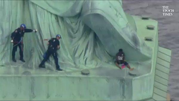 Emergency Service Unit officers had to scale the statue to remove Therese “Patricia” Okoumou, who had apparently climbed up to protest immigration policy, in New York City on July 4, 2018. (Screenshot/Fox News)