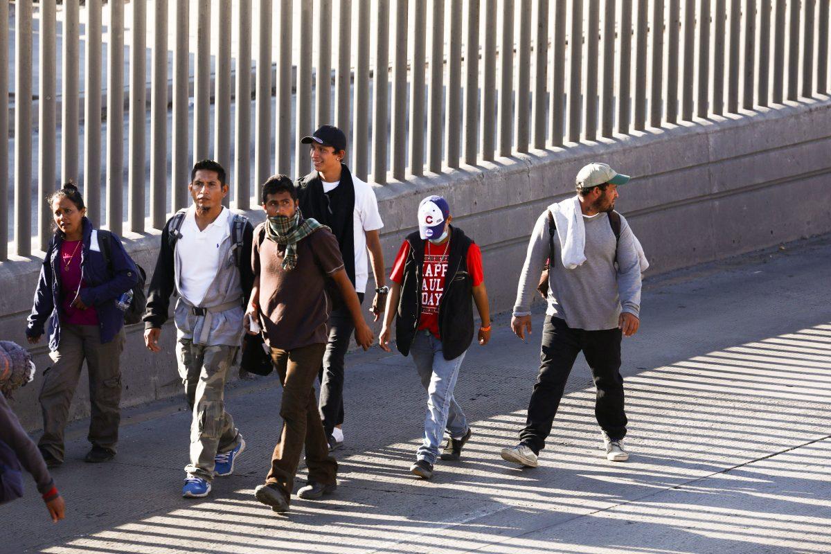 Migrants walk back to their camp after a failed attempt to rush the U.S. border and enter illegally, just west of the San Ysidro crossing in Tijuana, Mexico, on Nov. 25, 2018. The fence in the background is not the border, it's a secondary fence on the Mexico side. (Charlotte Cuthbertson/The Epoch Times)