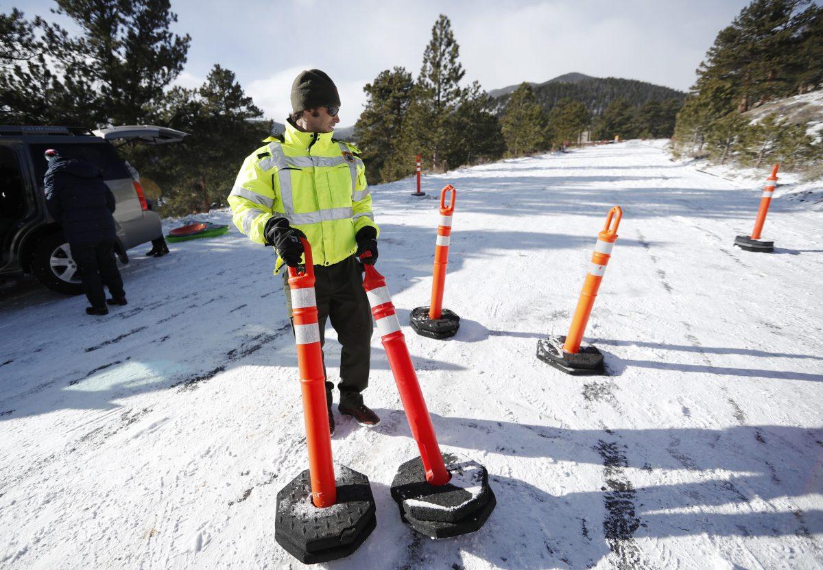 A park ranger drags pylons up Trail Ridge Road to block access after an overnight snow was left unplowed in Rocky Mountain National Park in Estes Park, Colo. on Dec. 22, 2018,. (AP Photo/David Zalubowski)