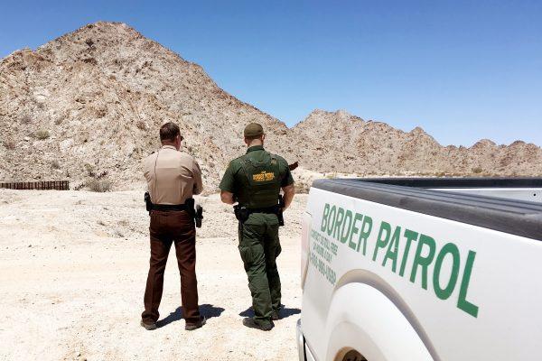 Sheriff Leon Wilmot speaks to a Border Patrol agent in the desert near Yuma, Ariz., by the U.S.–Mexico border on May 25, 2018. A small section of border fence can been seen on the left. (Charlotte Cuthbertson/The Epoch Times)