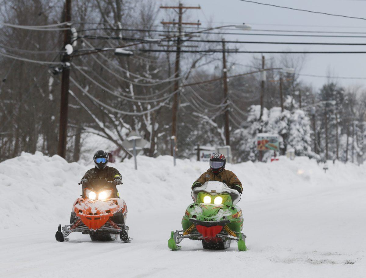 Volunteer firefighters ride snowmobiles down Clinton Street in West Seneca, N.Y. on Nov. 20, 2014. (AP Photo/Mike Groll)