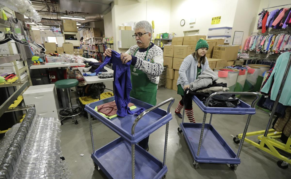 Chris Meyer, left, and Maddi Heim, fold and sort donated clothes at Treehouse, a nonprofit organization in Seattle that serves the needs of children in the foster-care system. The charity was one of several that received donations from the $11 million secret estate of Alan Naiman -- a social worker who died from cancer earlier in 2018 after living a private life of frugality and concern for children facing hardship. Dec. 21, 2018. (Ted S. Warren/AP)