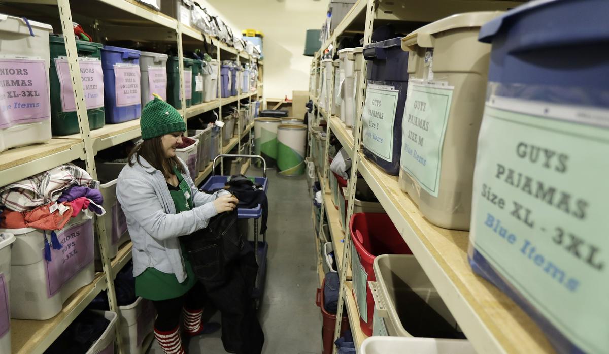 Maddi Heim folds and sorts donated clothes at Treehouse, a nonprofit organization in Seattle that serves the needs of children in the foster-care system. The charity was one of several that received donations from the $11 million secret estate of Alan Naiman -- a social worker who died from cancer earlier in 2018 after living a private life of frugality and concern for children facing hardship. Dec. 21, 2018. (Ted S. Warren/AP)