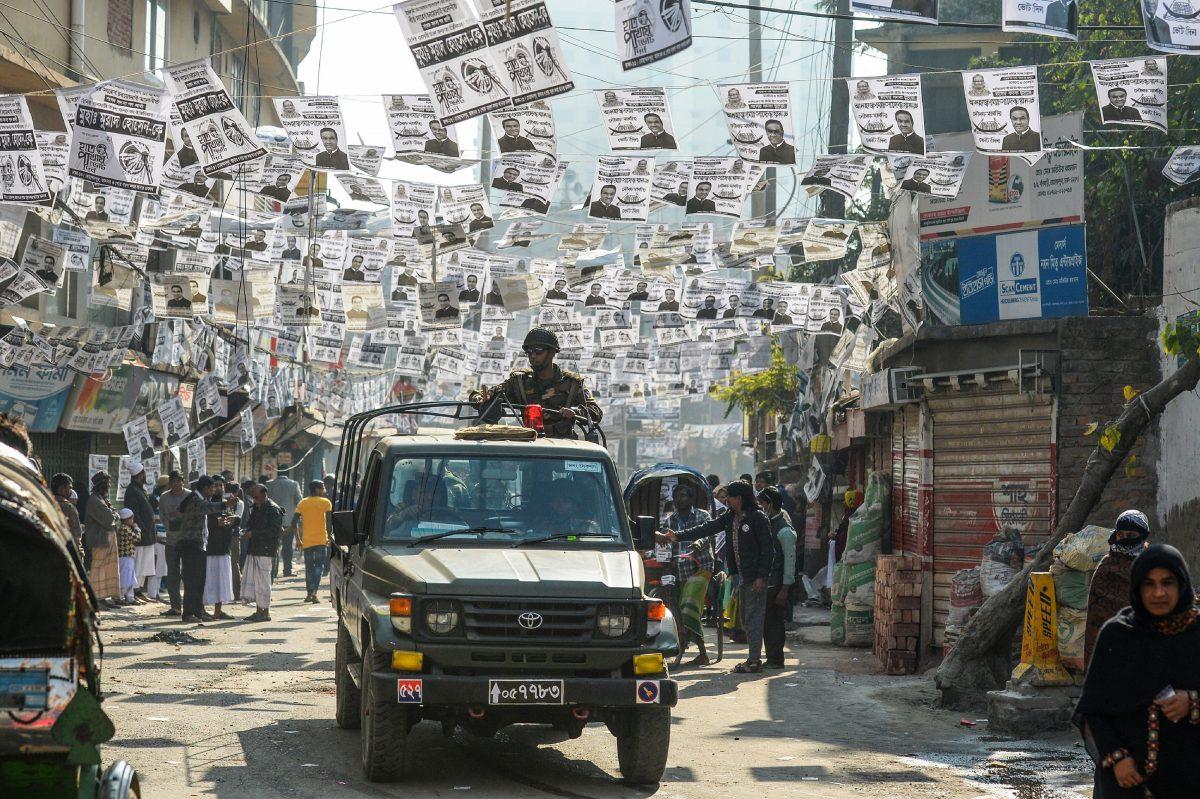 Bangladeshi army personnel drive a military vehicle through a street adorned with election posters near a polling station in Dhaka on Dec. 30, 2018. (Munis Uz Zaman/AFP/Getty Images)
