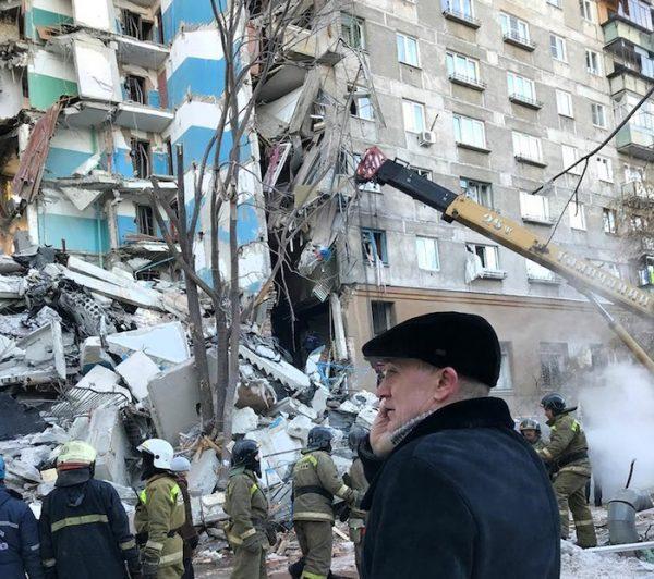 Governor of the Chelyabinsk Region Boris Dubrovsky (C), speaks on the phone as Emergency Situations employees work at the scene of a collapsed apartment building, on Dec. 31, 2018. (Chelyabinsk Region Governor Press Service photo via AP)