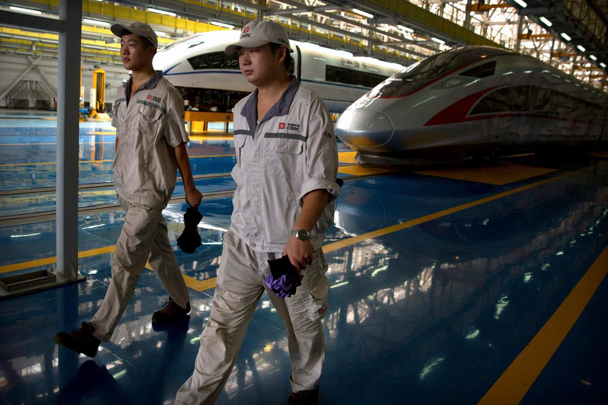 Workers walk past parked high-speed trains at a maintenance yard during a media tour ahead of the 2018 Forum on China-Africa Cooperation in Beijing, on Aug. 30, 2018. (AP Photo/Mark Schiefelbein)