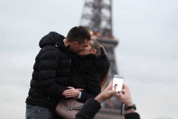 A couple of tourists kiss as they pose with the Eiffel Tower in background at the Trocadero esplanade in Paris on Dec. 31, 2018. (Zakaria Abdelkafi/AFP/Getty Images)