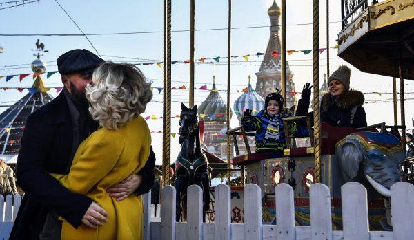 A couple kisses while visiting the Christmas and New Year market in front of St. Basil's cathedral on Red Square in Moscow on Dec. 16, 2018. (Photo by Alexander Nemenov/AFP/Getty Images)