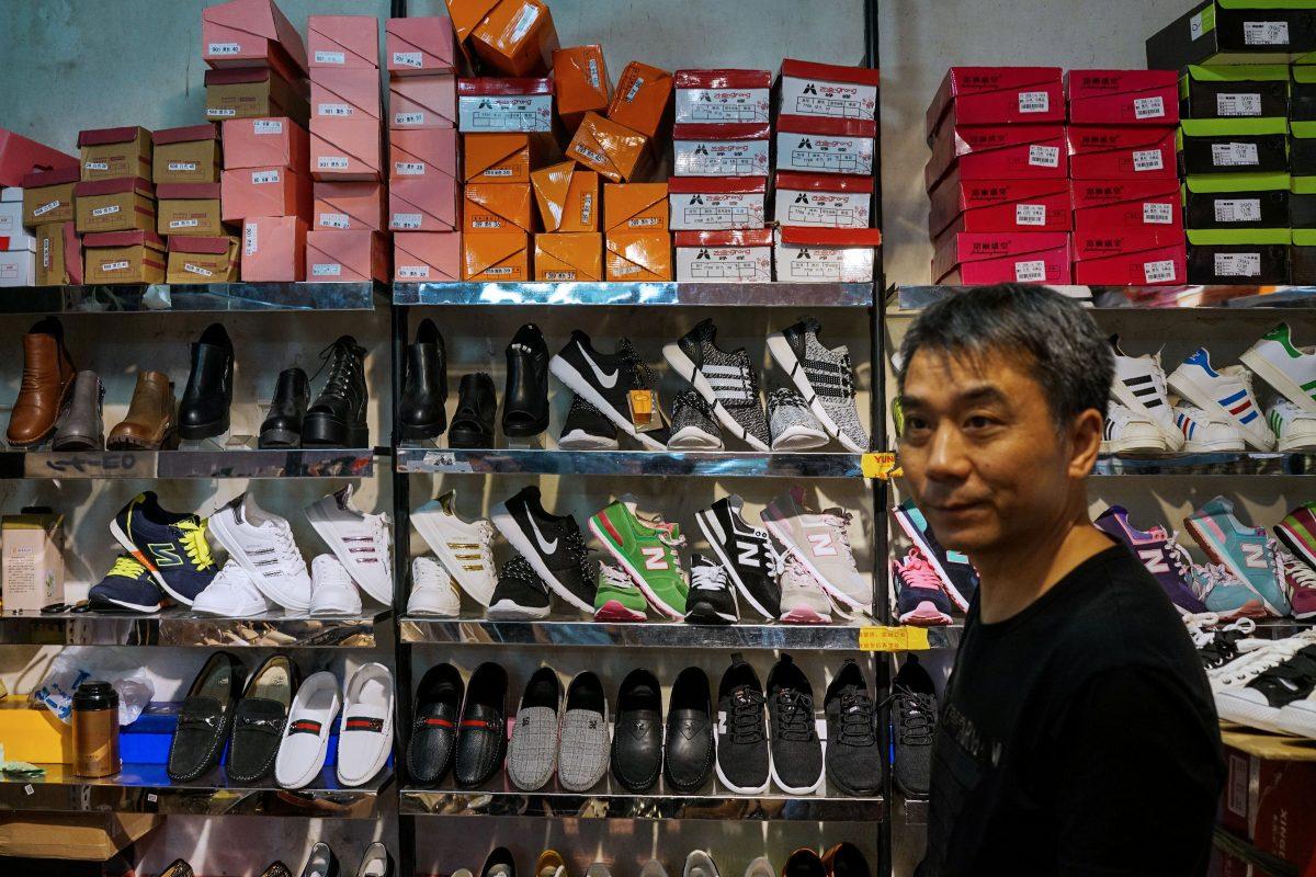 A Chinese salesman looks on as he sells copies of various American footwear brands inside a shopping complex in Shanghai, China, on Aug. 15, 2017. (Chandan Khanna/AFP/Getty Images)