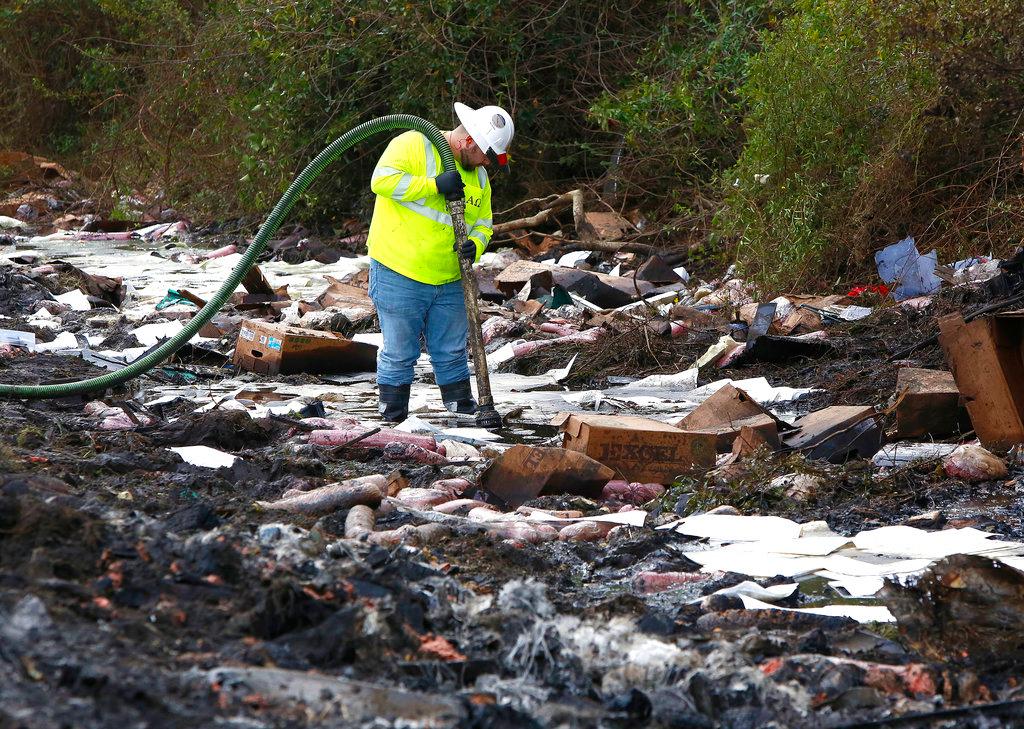 A worker with the environmental clean up company AAG Environmental works to remove fuel spilled at the scene of Thursday's multi-vehicle accident that caused multiple fatalities on Interstate 75 between Alachua and Gainesville, Fla., on Friday, Jan. 4, 2019. (Brad McClenny/The Gainesville Sun via AP)