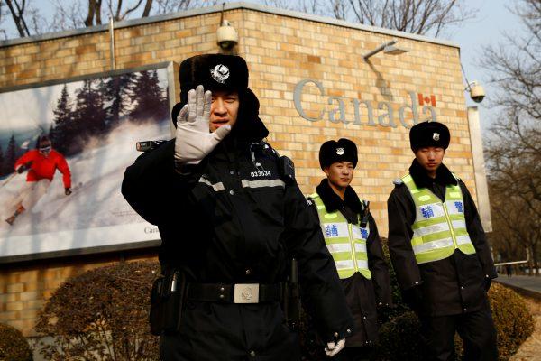 A police officer gestures at the photographer outside the Canadian embassy in Beijing on Dec. 20, 2018. (Reuters/Thomas Peter)