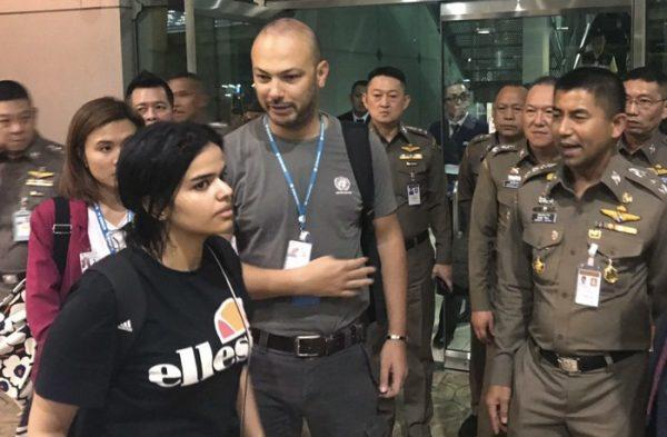 In this photo released by the Immigration Bureau, Saudi woman Rahaf Mohammed Alqunun, foreground walks by Chief of Immigration Police Maj. Gen. Surachate Hakparn, right, before leaving the Suvarnabhumi Airport in Bangkok, on Jan. 7, 2019. (Immigration police via AP)
