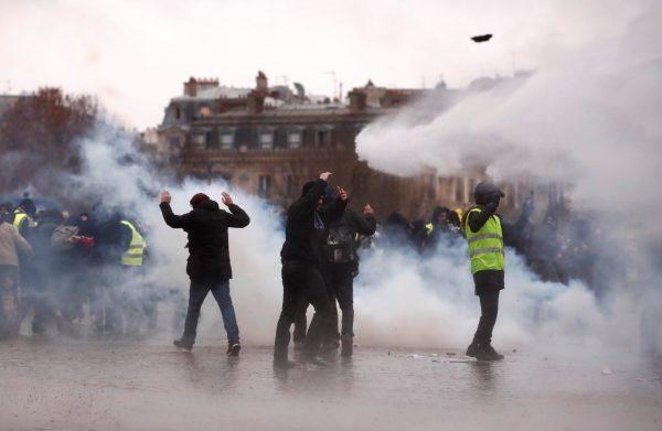 Protesters walk through tear gas during a demonstration of the "yellow vests" movement near the Arc de Triomphe in Paris, France, January 12, 2019. REUTERS/Christian Hartmann