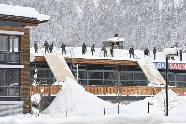 Solidiers from the Austrian Bundesheer clean a roof from snow in Waidring, Austrian province of Tyrol, on Jan. 12, 2019. (Kerstin Joensson/AP)