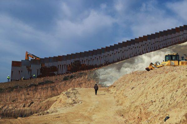 A construction crew works (L) as new sections of the U.S.-Mexico border barrier are installed replacing smaller fences on Jan. 11, 2019 as seen from Tijuana, Mexico. (Mario Tama/Getty Images)