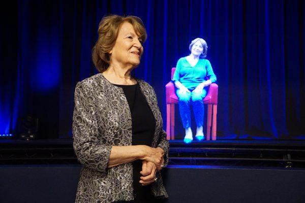 Holocaust survivor Fritzie Fritzshall stands in front of a hologram of herself at The Abe & Ida Cooper Survivor Stories Experience in the Illinois Holocaust Museum & Education Center in Skokie, Ill., in Oct. 2017. (Ron Gould/Illinois Holocaust Museum & Education Center via AP)