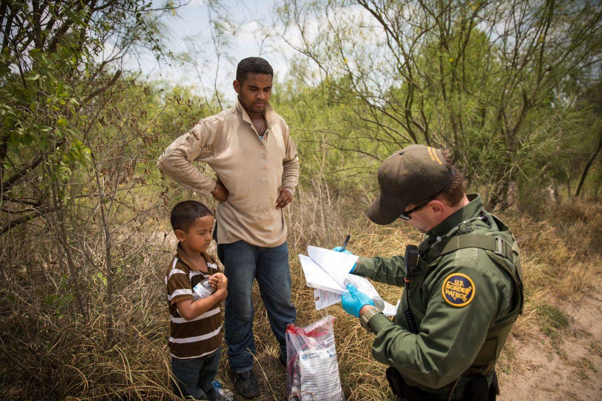 A Border Patrol Agent takes down information of a man and his son who crossed the Rio Grande River from Mexico into the United States in Hidalgo County, Texas, on May 26, 2017. (Benjamin Chasteen/The Epoch Times)