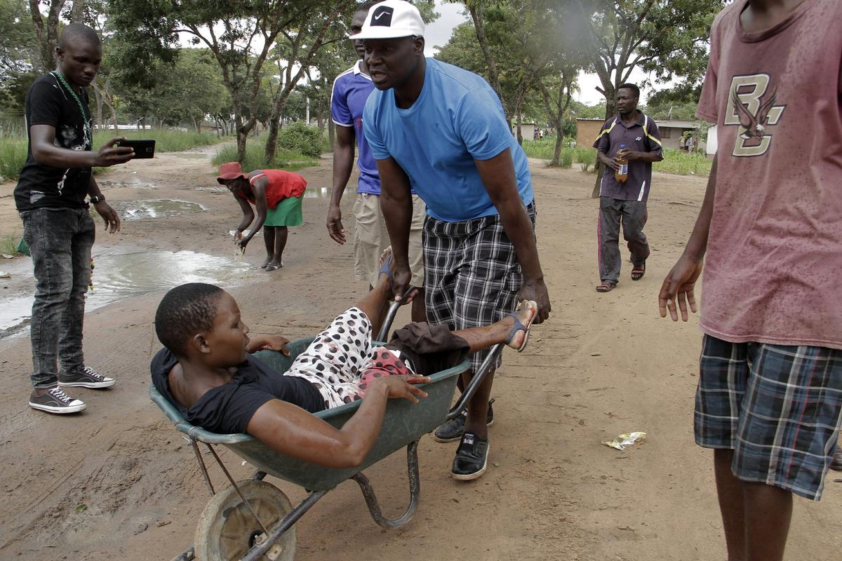 A woman with a wounded leg during clashes between protesters and police, is transported in a wheelbarrow, during protests over fuel hikes in Harare, Zimbabwe, Jan. 14, 2019. (Tsvangirayi Mukwazhi/AP Photo)