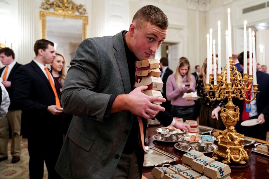 A Clemson player carries fast food hamburgers provided due to the partial government shutdown as the 2018 College Football Playoff National Champion Clemson Tigers are welcomed in the State Dining Room of the White House in Washington, on Jan. 14, 2019. (Joshua Roberts/Reuters)