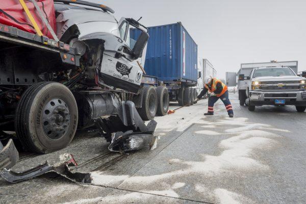 A Caltrans worker covers spilled fuel and liquids with absorbent while cleaning up after a multi-car collision along a foggy Interstate 15 in the Cajon Pass near Hesperia Calif., on Jan. 16, 2019. (James Quigg/The Daily Press/AP)