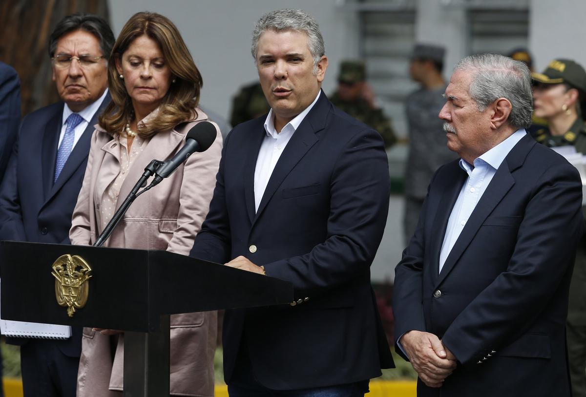 Colombia's President Ivan Duque gives a statement inside the General Santander police academy after a bomb exploded on the campus in Bogota, Colombia, Thursday, Jan. 17, 2019. At right is Defense Minister Guillermo Botero and at left is Vice President Martha Lucia Ramirez. (AP Photo/John Wilson Vizcaino)
